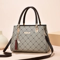 Taupe leather handbag with cat tassel and gold hardware on warm beige background - Light Maple & Coffee