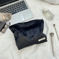 Close-up of black velvet cosmetic bag with zipper and logo in a lifestyle setting - Black