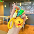 Detail of yellow lion cartoon keychain with green tree charm and braided wristlet strap - Pink Flower Headgear Dog