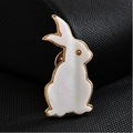 Détail de la broche lapin dorée avec pierre œil de chat blanc sur fond texturé sombre - Lapin Mignon