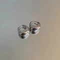 Vista ravvicinata di orecchini huggie a forma di U in argento su una superficie riflettente - Fibbia per orecchio a forma di U / Argento