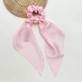 Detail of pink satin scrunchie with long ribbon tails on a textured beige background - Light Pink