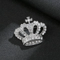 Macro shot of silver crown brooch with white rhinestones and cross on leather background - Crown Silver