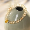 Detailed shot of yellow rutilated quartz beaded bracelet with gold hollow charms - Yellow Rutilated Quartz & White Crystal Beaded Bracelet