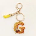 Detail of acrylic letter G keychain with honey bee pattern and a yellow tassel fringe - Letter G