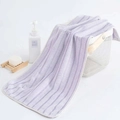 Absorbent purple striped coral fleece towel with delicate piping on a white basket - Purple