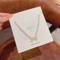 Close-up of a Korean style pearl necklace featuring a golden bow pendant on a card - Pearl Bowknot Style (X901) / Gold/White Pearl