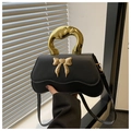 Detail der schicken schwarzen Handtasche mit Wellenrand und goldener Schleifenschnalle - Schwarz