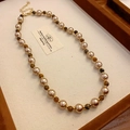 Détail d'un collier de perles brunes lustrées et perles dorées sur un plateau à bijoux - Collier de Perles Marron Vintage