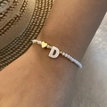 Detail of beaded bracelet featuring a white letter D shell charm and golden heart bead - Letter D