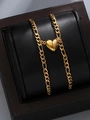 Detail view of a gold heart pendant and Figaro chain on a black leather display stand - Gold