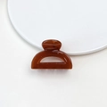 Detail of amber brown jelly hair claw clip with glossy resin finish on white plate - Jelly Mini Claw - Semi-circle Deep Orange