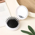 White folding portable round hairbrush with built-in mirror on a minimalist tray - White