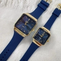 Coppia di orologi dorati quadrati con cinturini in silicone blu su tessuto bianco - Quadrante Blu Cinturino Blu