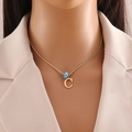 Detail of gold necklace with letter C pendant and blue evil eye bead on a female model - Letter C (N1339)