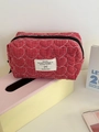 Close-up of heart-quilted red gingham cosmetic bag with white label on pink storage box - Red