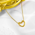 Elegant gold-plated hollow heart pendant necklace with a fine snake chain on stone surface - Hollow Heart Necklace / Gold + Snake Chain