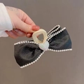 Elegant black tulle bow hair claw with pearl trim and heart detail in hand - Black Bow Heart-Claw Clip