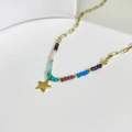 Bunte Perlenkette mit minimalistischem goldenem Sternanhänger auf weißer Keramik - Einheitsgröße / Mehrfarbig