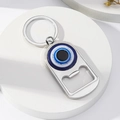 Detail view of silver metal evil eye bottle opener keychain on a white stone display - Style 2 (2)