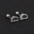 Detail view of silver screw-back animal paw stud earrings on black textured surface - Footprint / Steel