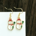 Detail shot of snowman earrings with red and green enamel on a wooden background - Classic Red Scarf Snowman