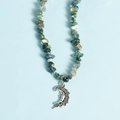 Green crystal chip necklace featuring a silver moon face pendant on a light blue background - Moss Agate Moon