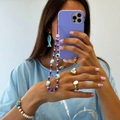 Detail of colorful beaded phone lanyard with evil eye and smiley charms on purple case - Purple Series Smiley Evil Eye