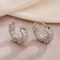 Pendientes de aro plateados con circonitas texturizadas sobre fondo elegante - Plateado