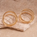 Detalle de pendientes circulares trenzados multicapa dorados sobre base de piedra natural - Dorado
