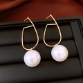 Macro shot of geometric gold earrings with white pearls on a black jewelry tray - Gold Line White Pearl Geometric Earrings