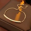Dettaglio macro di un bracciale dorato regolabile con zirconi arcobaleno su astuccio - Oro con Multicolore