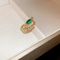 Dettaglio del ear cuff a serpente dorato con gemma verde e zirconi incastonati - Clip per orecchio a serpente verde