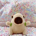 Plush capybara keychain with green backpack and golden carabiner on colorful foam balls - Turtle Backpack Light Brown + Gold Clip