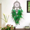Handmade dream catcher with green feathers and brown beads hanging on white wall - Green