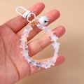 Detailed shot of star beads keychain with white bell and iridescent acrylic charms - White