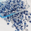 Detail of 6mm-8mm blue crackle glass beads spilling from a bowl onto white fabric - 8mm / Ink Sea Blue