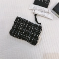 Detail of tweed coin purse with white zipper and tassel on a quilted white surface - Tweed Black