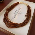 Detail of multi-strand beaded necklace with metallic clasp in a vintage jewelry box - Coffee