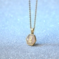 Gouden ketting met zeshoekige hanger, witte schelp inlegwerk en letter E detail - Letter E
