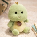 Cute green plush dinosaur toy with yellow belly sitting on a white fluffy rug - Sitting Dinosaur