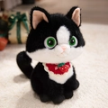 Cute black and white plush cat doll with a red strawberry bib on soft carpet - Christmas Style