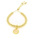 Detail van een gouden kralenarmband met een lichtroze emaille letter T hanger sieraad - Letter T