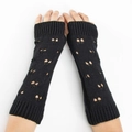 Macro detail of black knitted arm warmer featuring butterfly-shaped cutout pattern - Black
