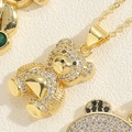 Vue macro d'un pendentif ours en or avec zircones blancs et yeux émeraude sur chaîne - Ours en Zircon