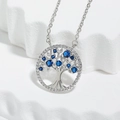Silver Tree of Life necklace featuring vibrant blue cubic zirconia on a white stand - Blue