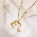 Macro detail of gold titanium necklace featuring letter E pendant and small cube charm - Gold Initial E (8847)