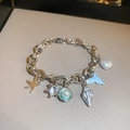 Detail van zilveren bedelarmband met zeester-, schelpen- en blauwe vissenstaarthangers - Nr. 2 Marien Thema (HB2972) / Zilver