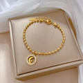 Close-up of golden stainless steel bead bracelet with a crystal crescent moon and star pendant - Gold