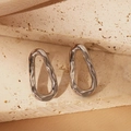 Detailed macro view of silver hollow heart earrings with textured metallic finish - Wave Pleated Oval Style